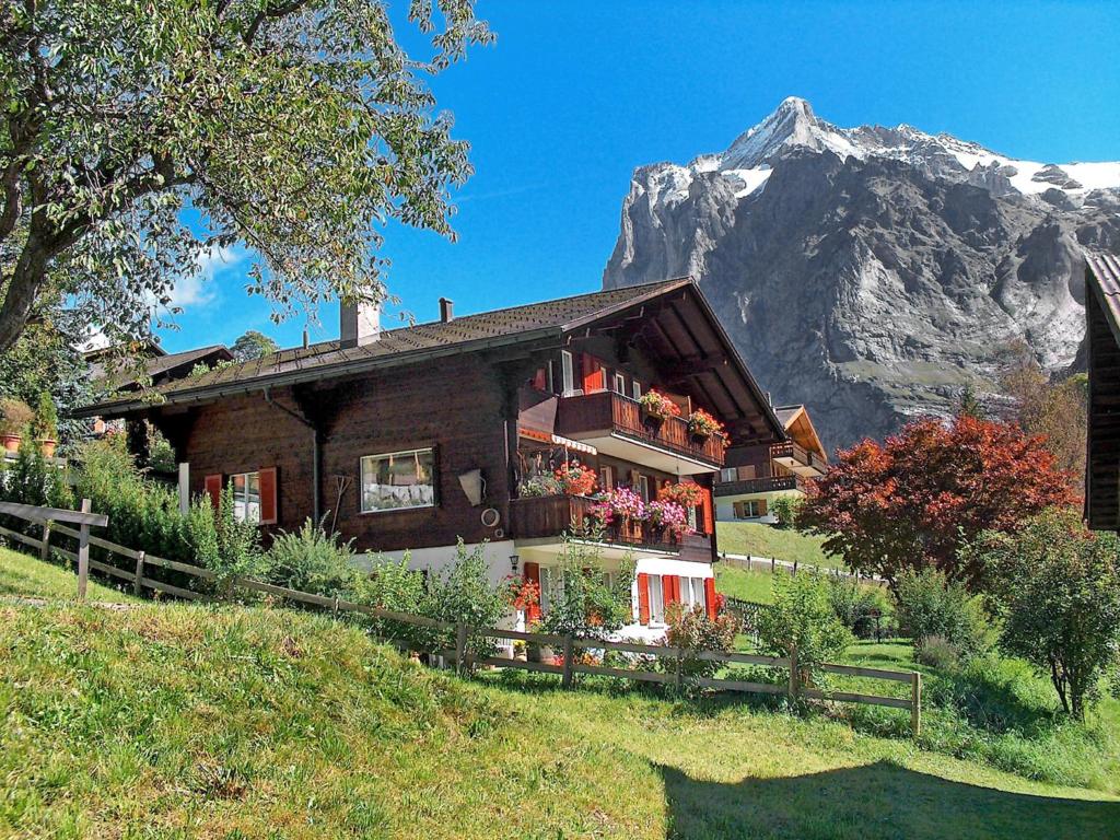 una casa su una collina con una montagna sullo sfondo di Apartment Chalet Bärgsunna-1 by Interhome a Grindelwald