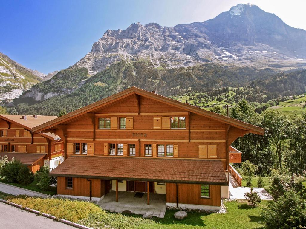 uma grande casa de madeira com montanhas ao fundo em Apartment Chalet Eiger-2 by Interhome em Grindelwald