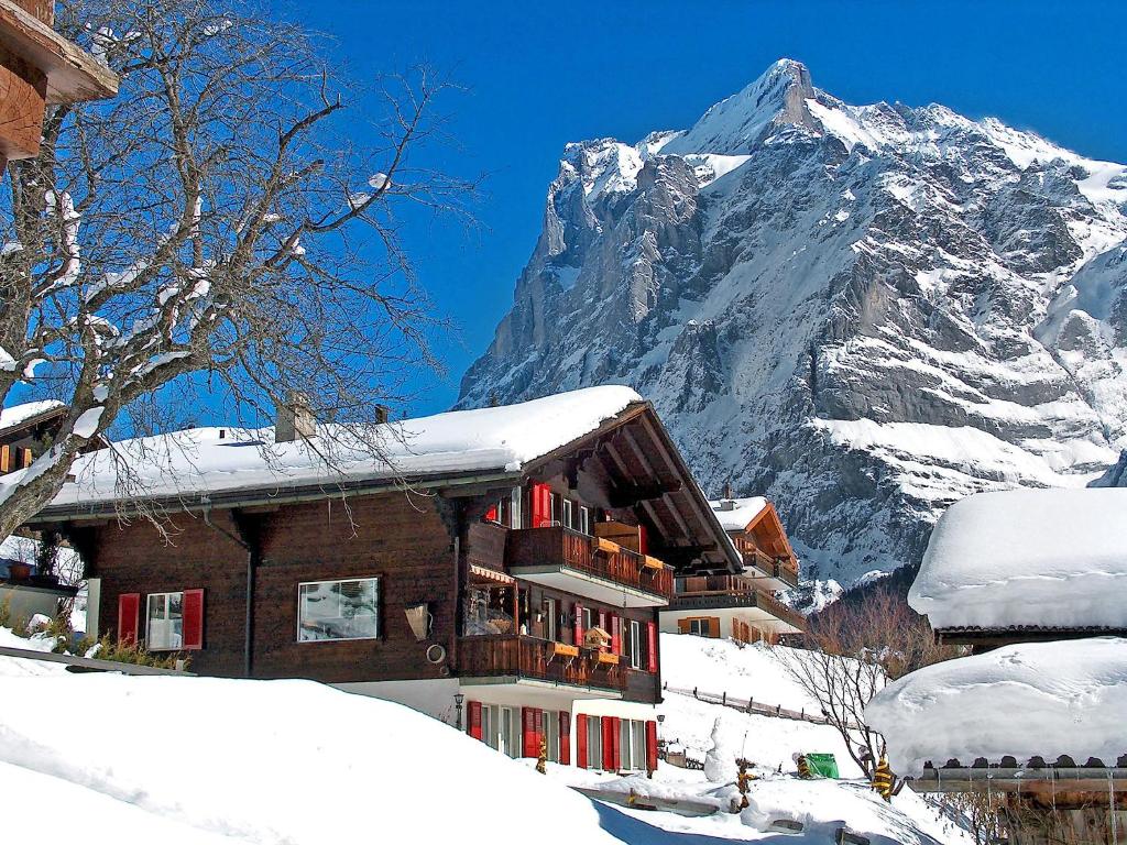 un edificio innevato con una montagna sullo sfondo di Apartment Chalet Bärgsunna-4 by Interhome a Grindelwald