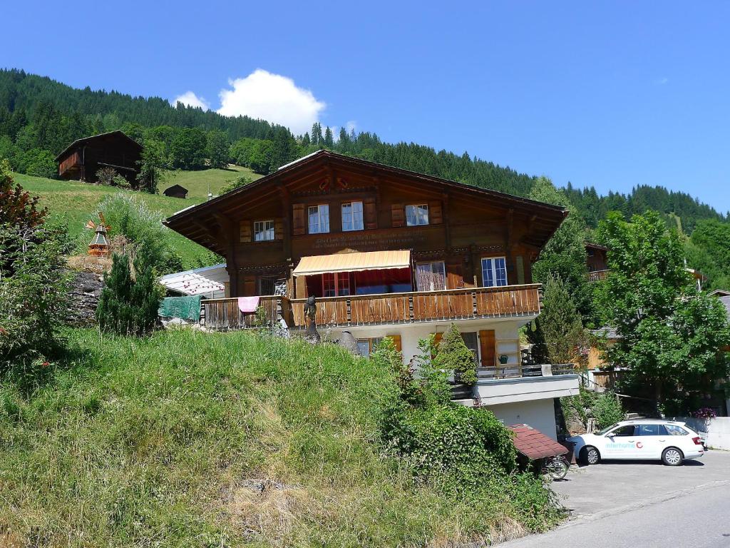 a large wooden house on a hill with a car at Apartment Chalet Seeberg by Interhome in Lenk