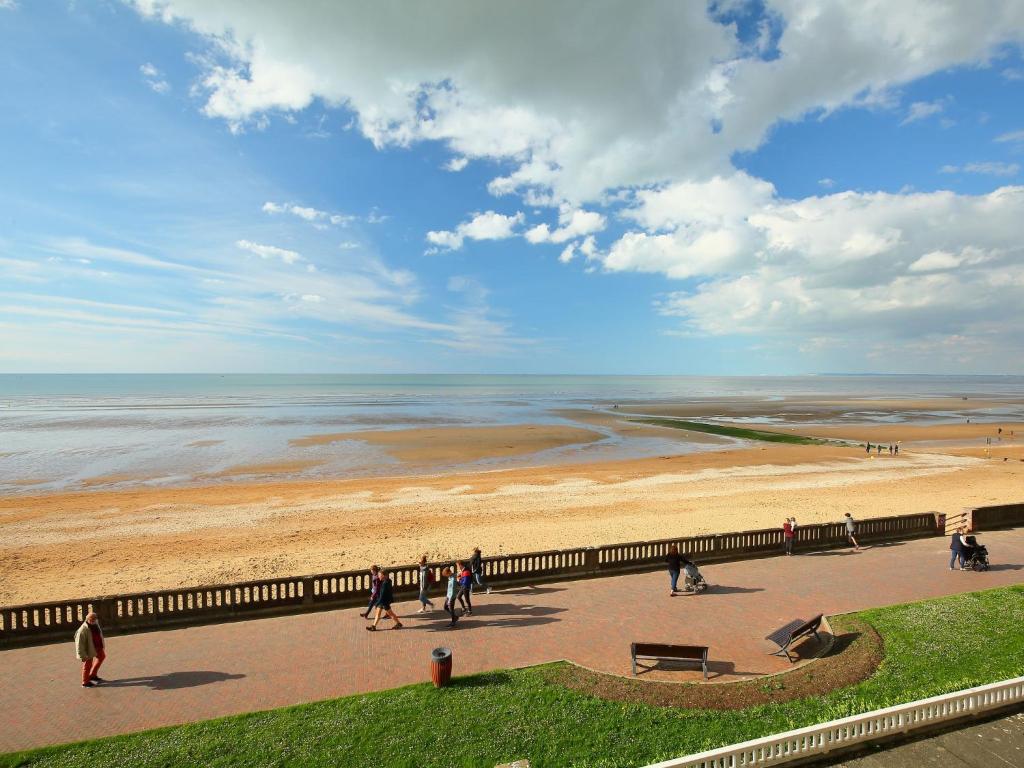 a group of people walking on a sidewalk near the beach at Apartment Isabelle-1 by Interhome in Cabourg