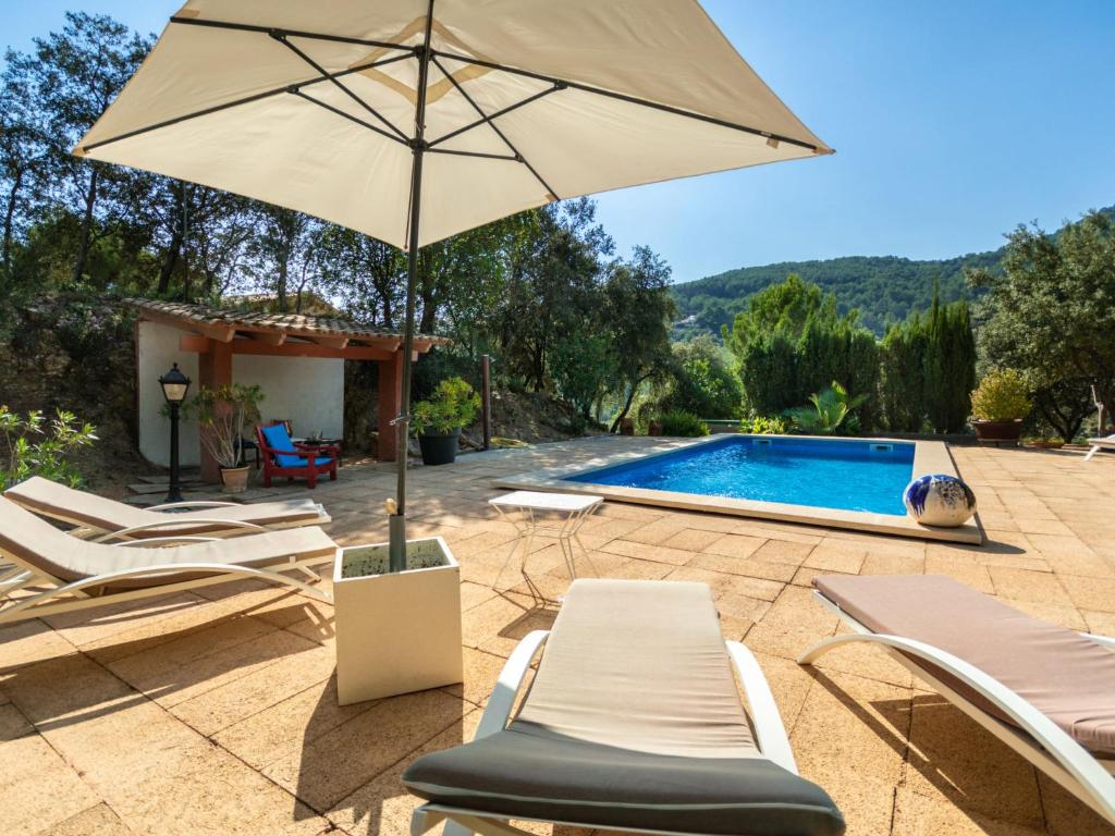 een patio met stoelen en een parasol naast een zwembad bij Holiday Home S'Hort des Verger - EPO100 by Interhome in Esporles