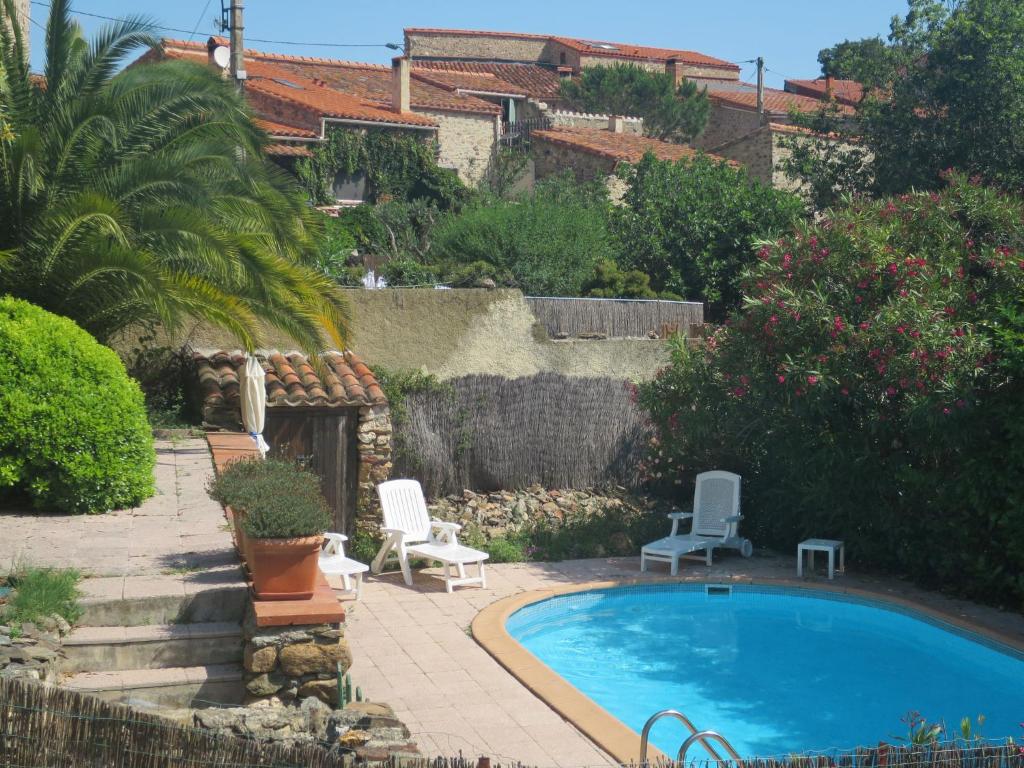 Tordères的住宿－Holiday Home Oleander by Interhome，一个带两把白色椅子的庭院内的游泳池
