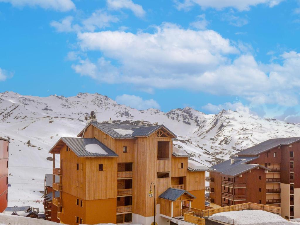 a building with snow covered mountains in the background at Apartment Les Cimes de Caron-7 by Interhome in Val Thorens