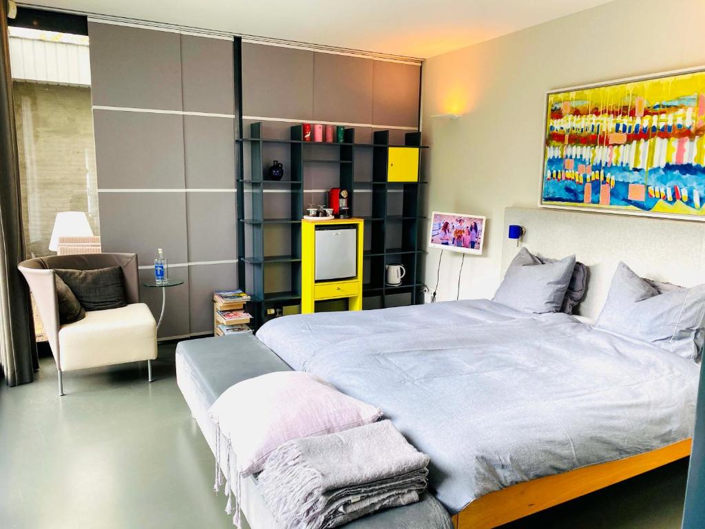 um quarto com uma cama grande e uma cadeira em B&B Winterresidentie em Tilburg