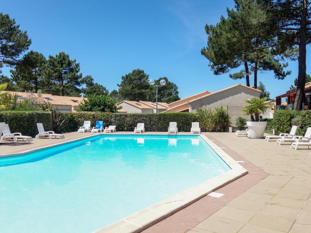 a large swimming pool with lounge chairs around it at Holiday Home Hameau de Talaris-4 by Interhome in La Palmyre