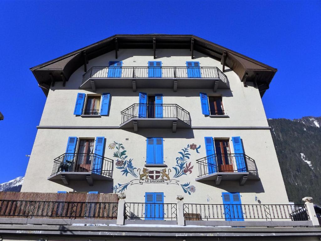 un bâtiment doté de fenêtres bleues et d'une fresque murale. dans l'établissement Apartment Le Savoisien by Interhome, à Chamonix-Mont-Blanc