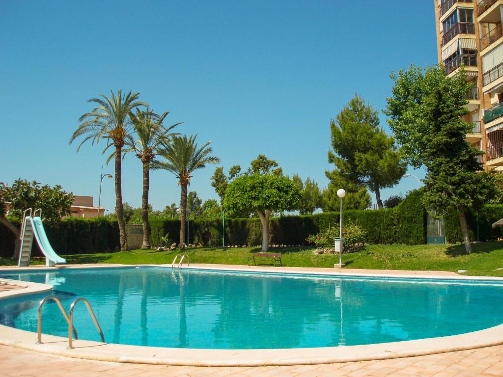 einen Pool mit Rutsche und Palmen in der Unterkunft Apartment Las Cinco Torres by Interhome in El Campello