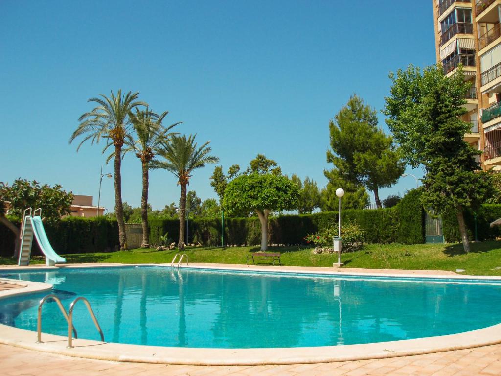 a swimming pool with a slide and palm trees at Apartment Las Cinco Torres by Interhome in El Campello