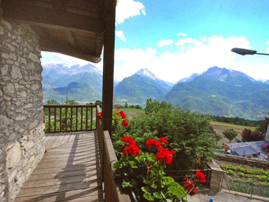 a balcony with red flowers and mountains in the background at Apartment Grand Sarriod-3 by Interhome in Saint Nicolas