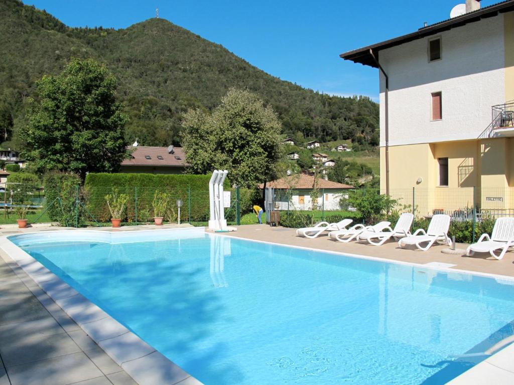 a large swimming pool with chairs and a house at Apartment Emilio-4 by Interhome in Ledro