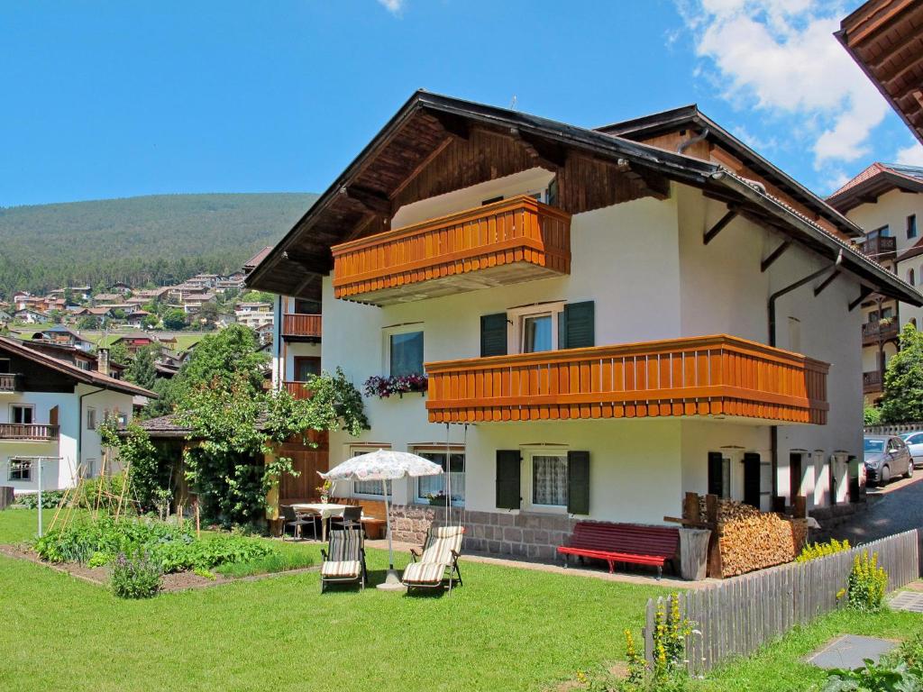 a house with a balcony and chairs on a yard at Apartment Demetz by Interhome in Ortisei