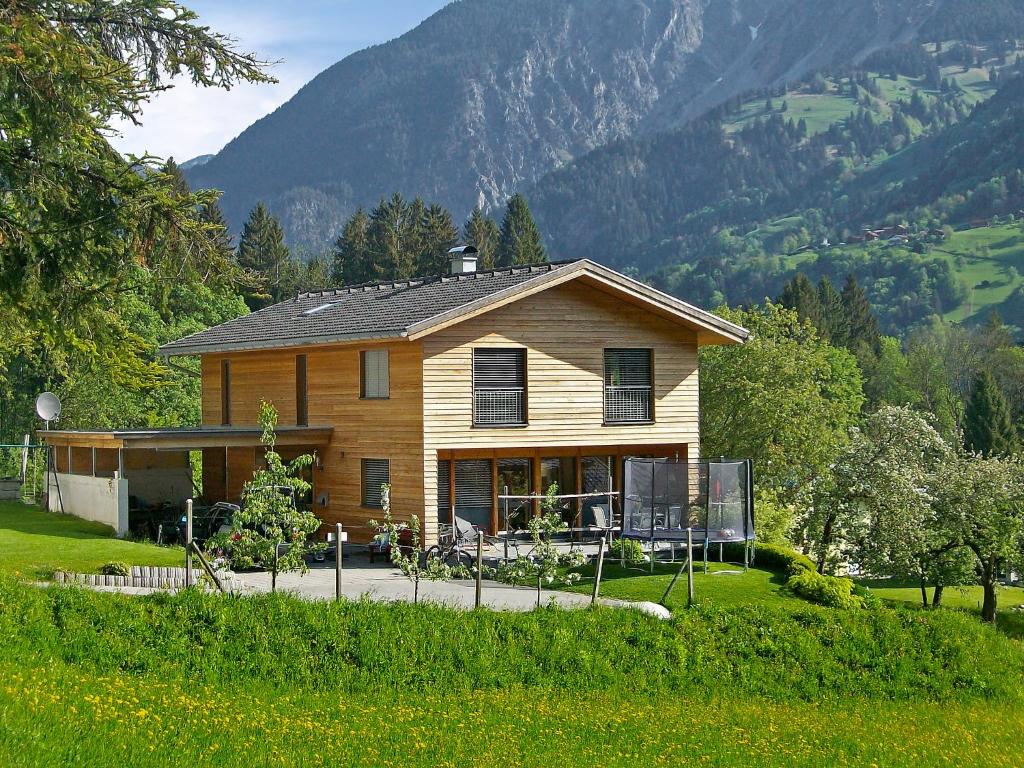a house in a field with mountains in the background at Apartment Corinna by Interhome in Vandans