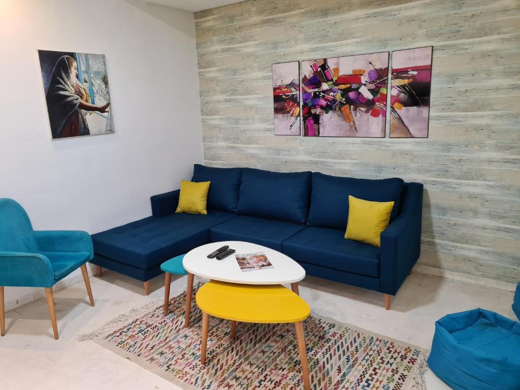 a living room with a blue couch and a table at Appartement Elyssa in Tunis