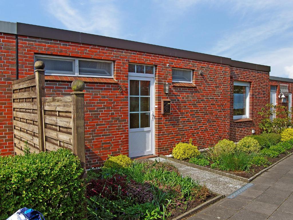 a red brick building with a door and a fence at Holiday Home Seefalke by Interhome in Norddeich