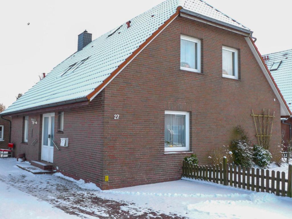 ein rotes Backsteinhaus mit einem Zaun im Schnee in der Unterkunft Apartment Schonerweg by Interhome in Norddeich