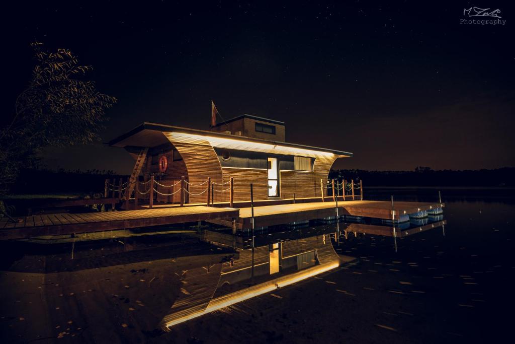 a house on a dock in the water at night at Houseboat Ślesin in Ślesin