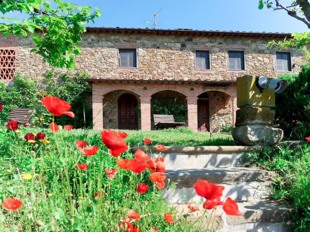 a stone building with red flowers in front of it at Holiday Home Agrumi by Interhome in Montevettolini