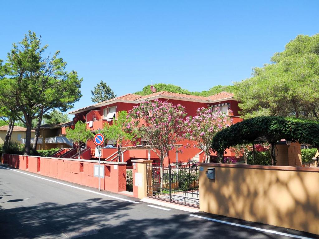 ein rotes Gebäude mit einem Zaun neben einer Straße in der Unterkunft Apartment Campeggio del Forte-1 by Interhome in Marina di Bibbona