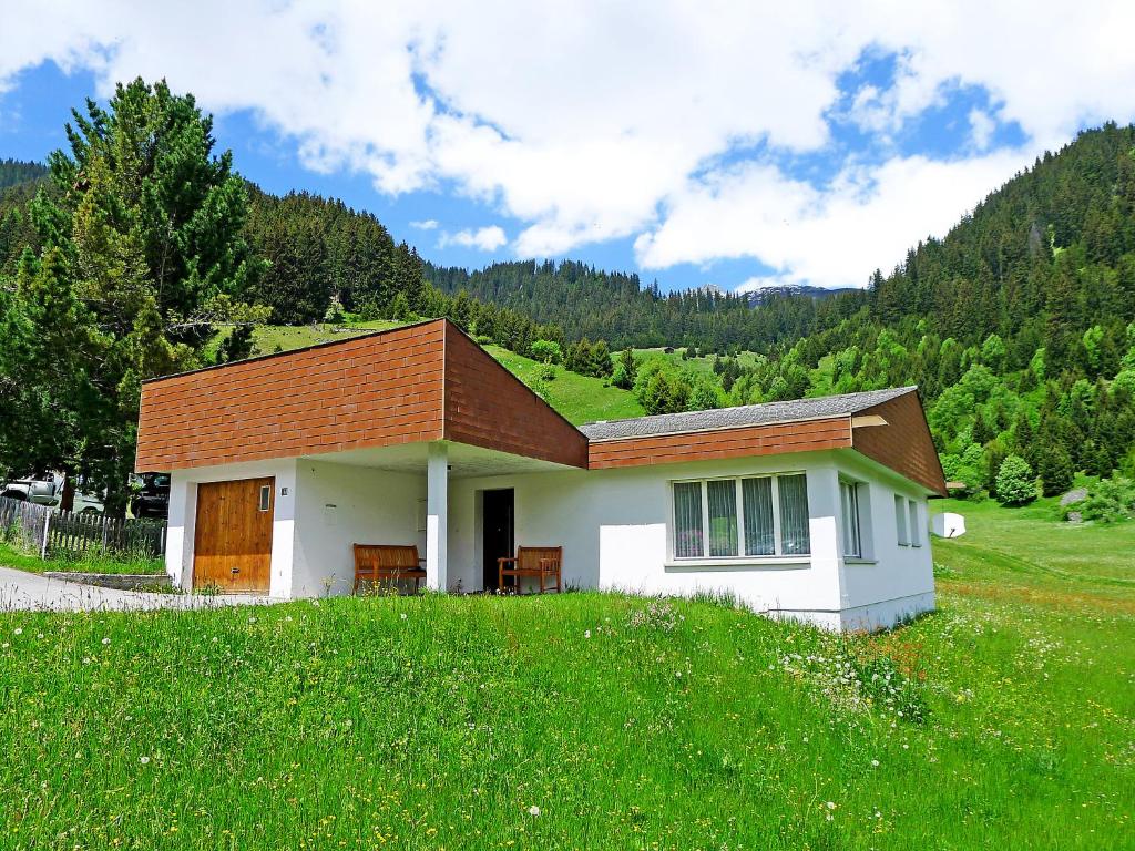 a small white house in a field of green grass at Holiday Home Peisel by Interhome in Disentis