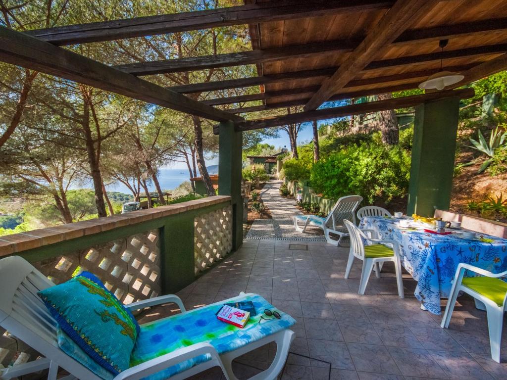 patio ze stołami i krzesłami oraz pergolą w obiekcie Holiday Home Piccola Oasi-4 by Interhome w mieście Capoliveri