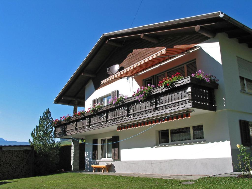 a white house with a balcony with flowers on it at Apartment Tanno by Interhome in Alvaschein