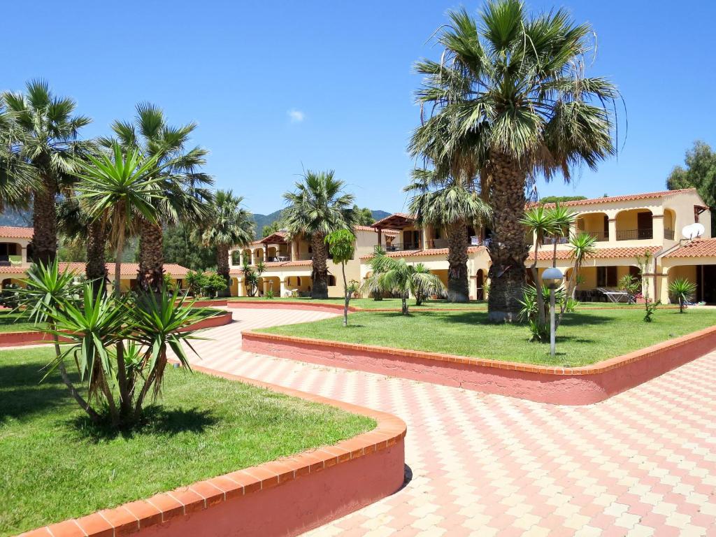 a courtyard with palm trees and a building at Apartment 4 Mori- Residence - MUV100 by Interhome in Costa Rei