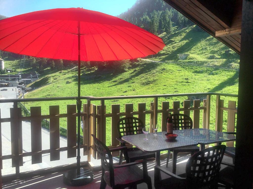 a table and chairs with a red umbrella on a balcony at Apartment Dents Rousses B4 by Interhome in Siviez