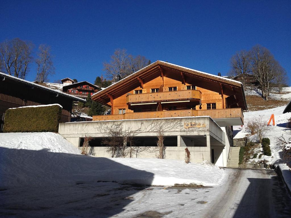 un gran edificio de madera con nieve delante en Apartment Chalet am Reeti by Interhome, en Grindelwald