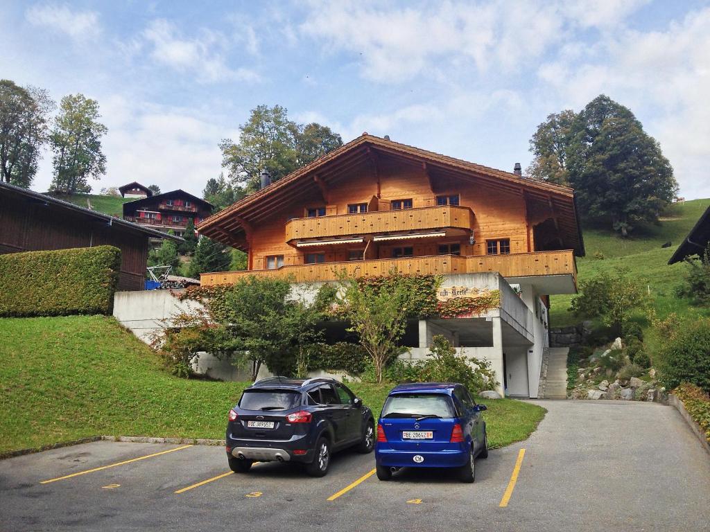 dos autos estacionados en un estacionamiento frente a un edificio en Apartment Chalet am Reeti by Interhome en Grindelwald