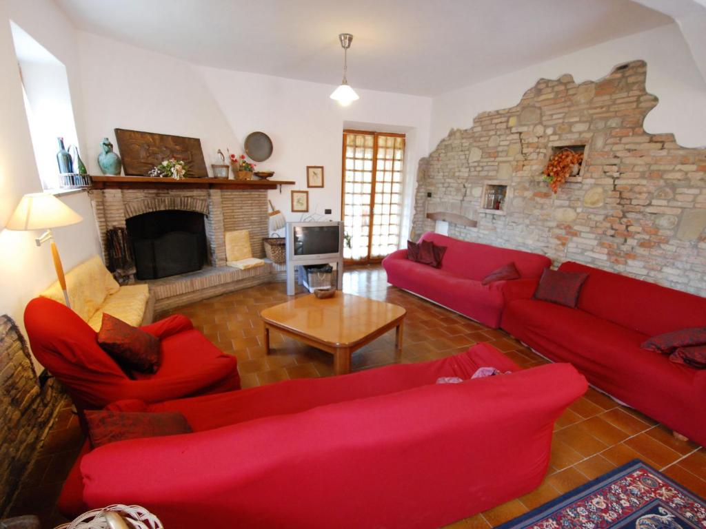 a living room with red couches and a stone wall at Holiday Home Maria Rosaria by Interhome in Ginestreto