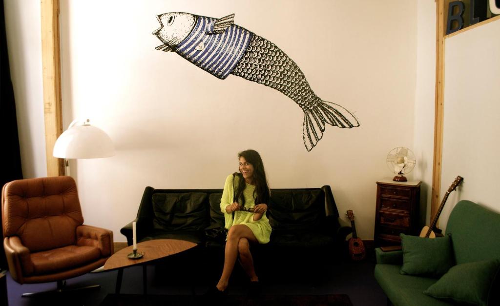 リスボンにあるグッドナイト ホステルの魚の壁掛けの部屋のソファに座る女性