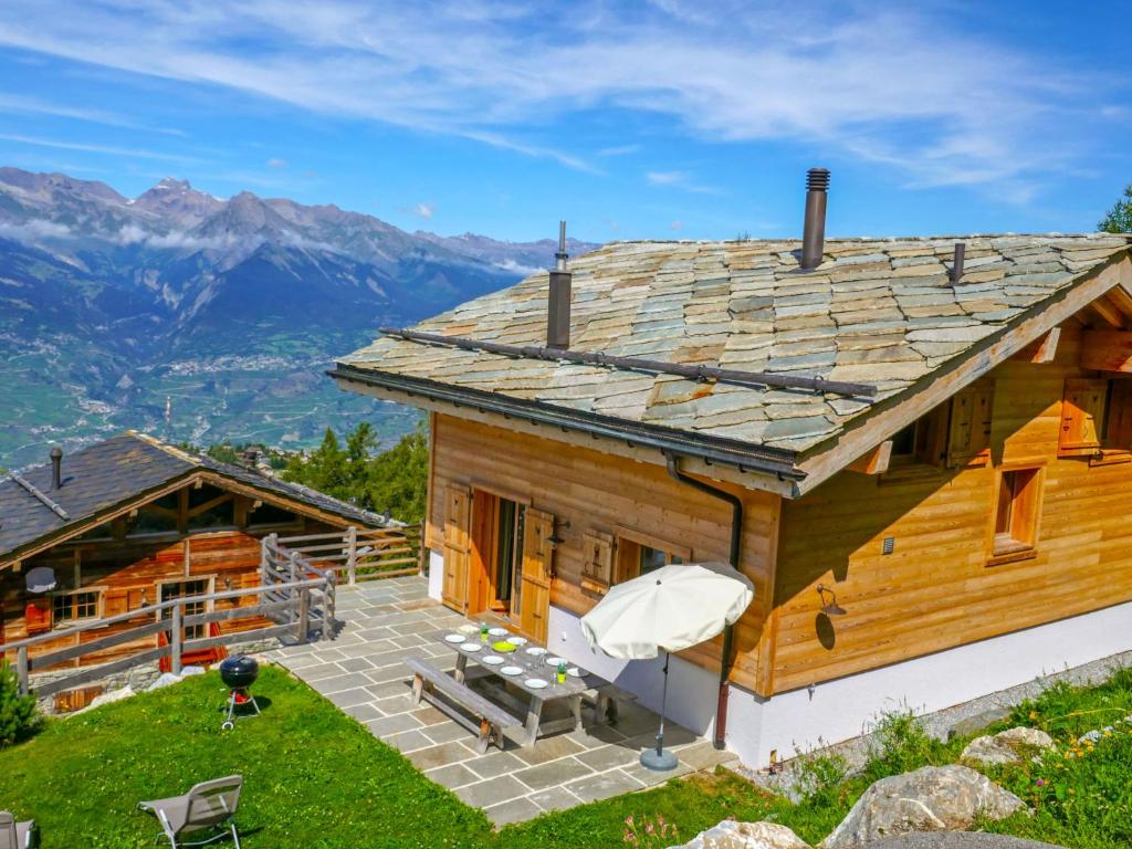 a log house with a patio and mountains in the background at Chalet Chalet Jadi by Interhome in Nendaz