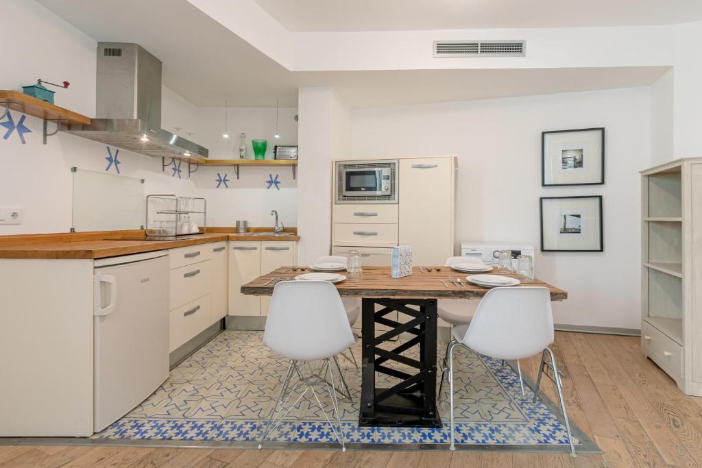 una cucina con tavolo in legno e armadietti bianchi di Hércules XCI Apartments a Siviglia
