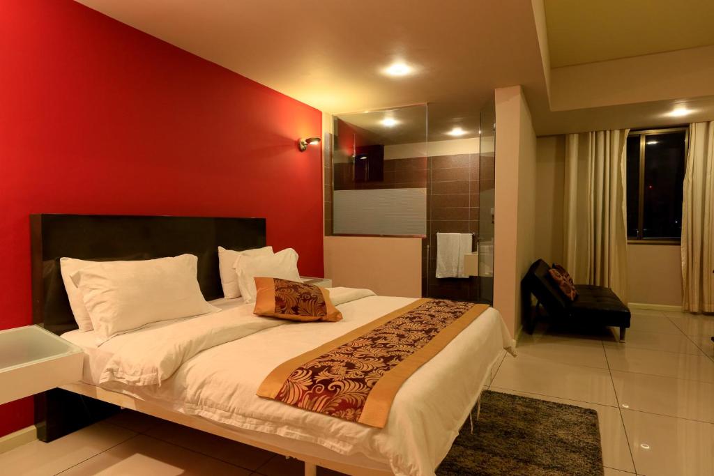 1 dormitorio con 1 cama grande y pared roja en Vienna City Hotel, en Tema