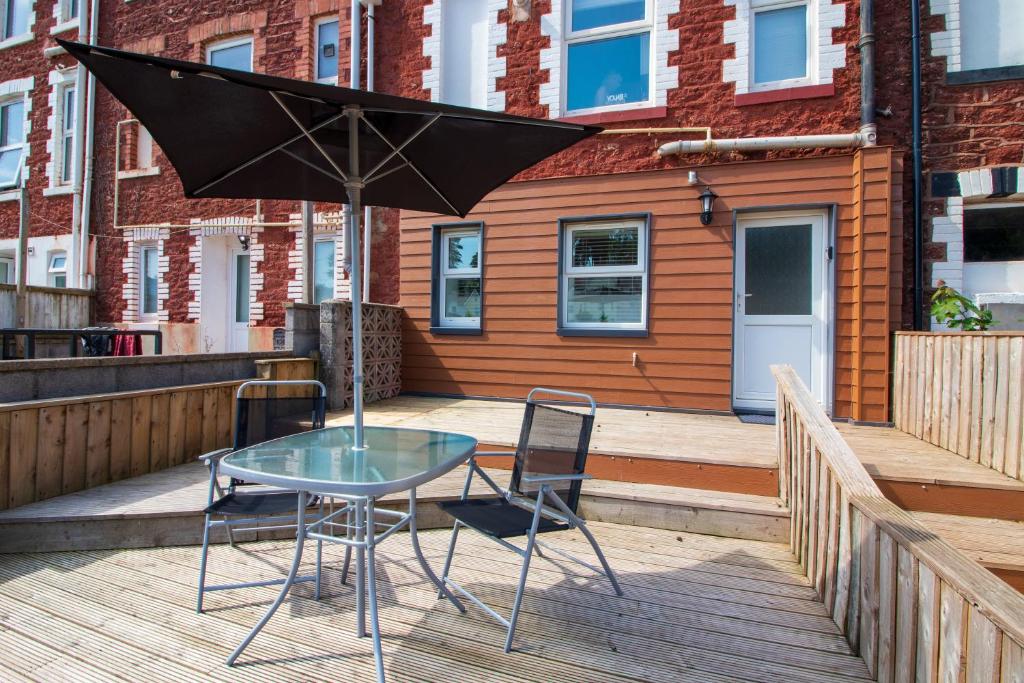 a table and two chairs and an umbrella on a deck at Stylish Studio in the Heart of the English Riviera in Torquay