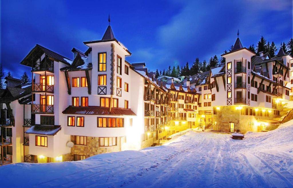 un grand bâtiment dans la neige la nuit dans l'établissement Pamporovo Apartment The Castle, à Pamporovo