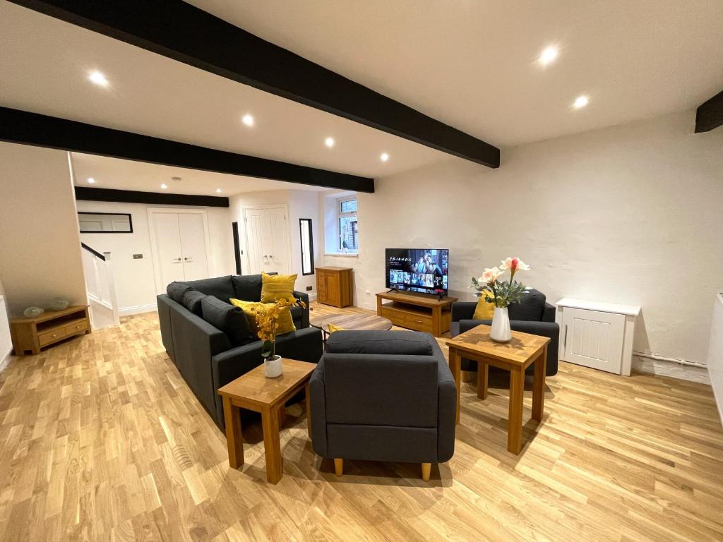 a living room with a couch and chairs and a tv at Yr Hen Bopty (The Old Bakery) in Pontypridd