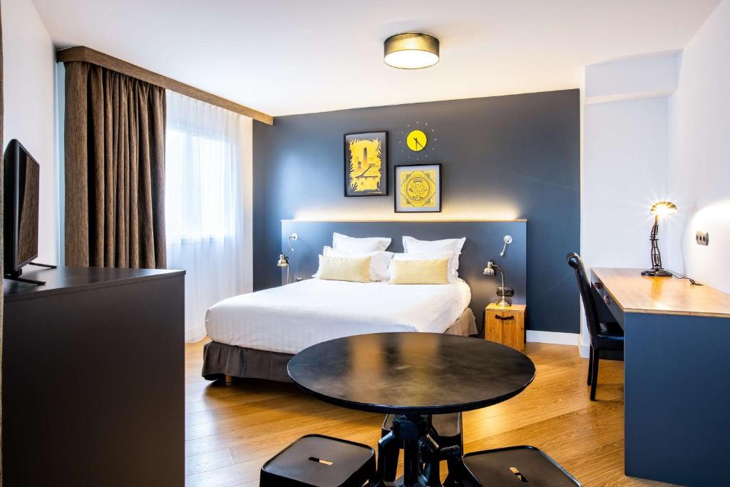 Pokój hotelowy z łóżkiem, stołem i biurkiem w obiekcie Best Western Plus Suitcase Paris La Défense w mieście Bois-Colombes