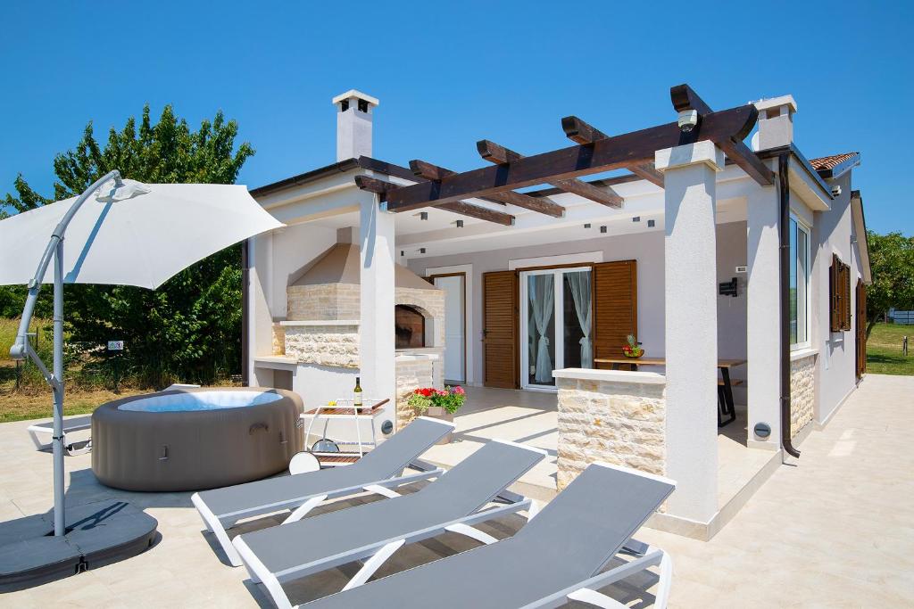 a patio with chairs and an umbrella and a house at Villa Irena in Medulin