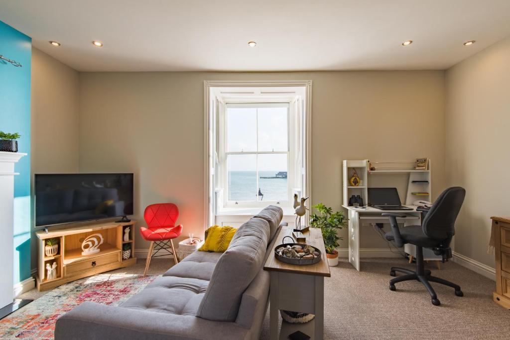 een woonkamer met een bank en een bureau bij Pier View - beautiful sea view apartment in Deal in Kent