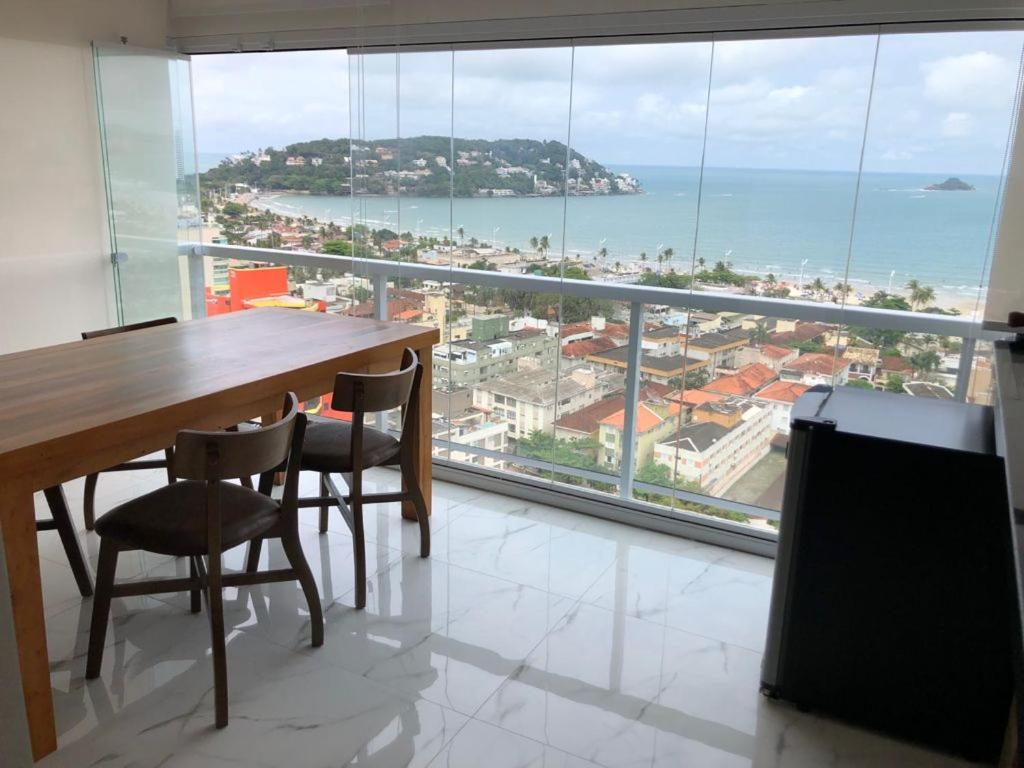 a dining room table with chairs and a view of the ocean at Maravilhoso apartamento vista mar Enseada Guarujá in Guarujá