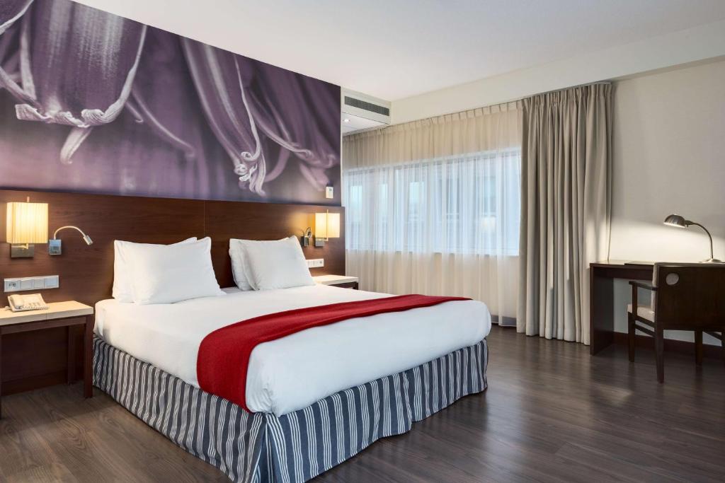 a hotel room with a large bed and a large window at NH Amersfoort in Amersfoort
