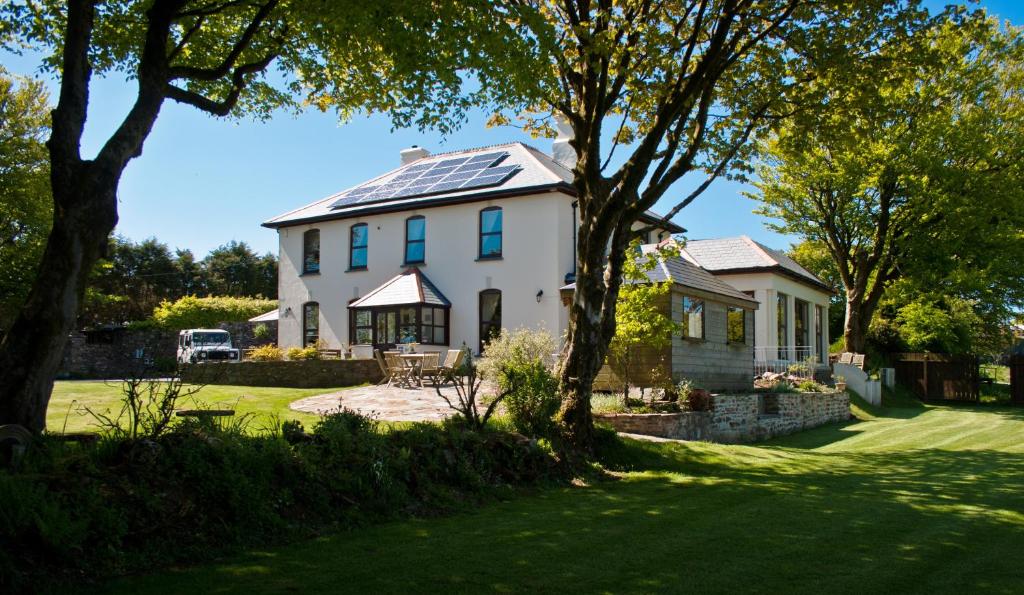 Casa blanca con paneles solares en el techo en Pendragon Country House, en Camelford