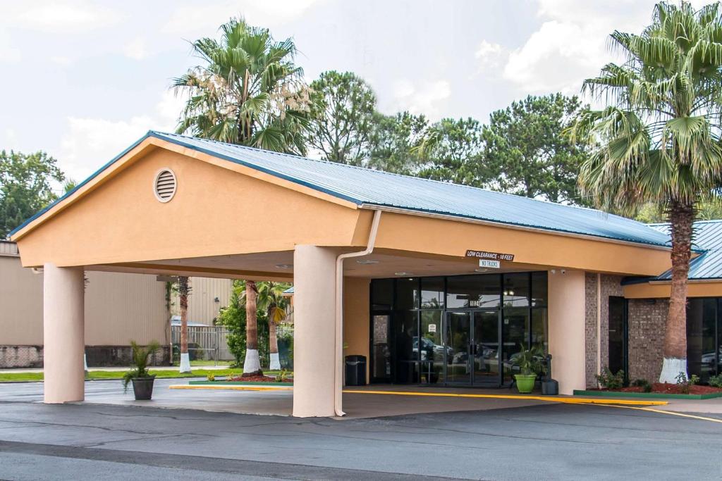 un bâtiment avec un toit bleu et des palmiers dans l'établissement Quality Inn Hinesville - Fort Stewart Area, Kitchenette Rooms - Pool - Guest Laundry, à Hinesville