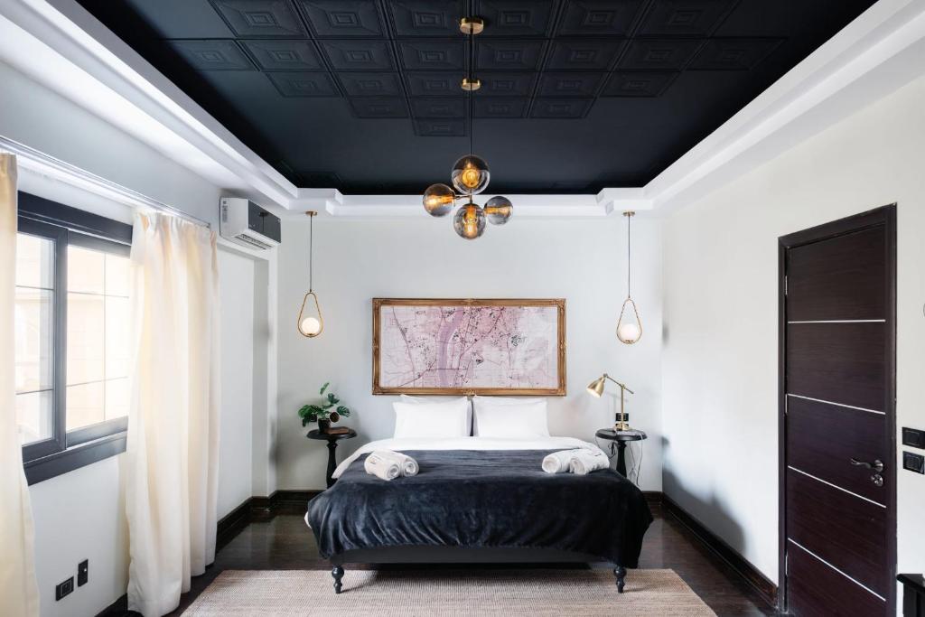 Schlafzimmer mit einem Bett mit schwarzer Decke in der Unterkunft The Bold Parisian House - Steps From The Best Mall in Cairo in Kairo