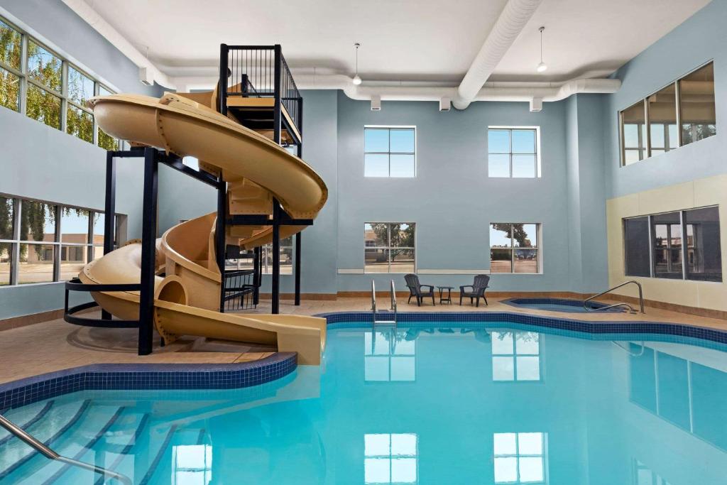 a indoor swimming pool with a slide in a building at Wingate by Wyndham Lethbridge in Lethbridge