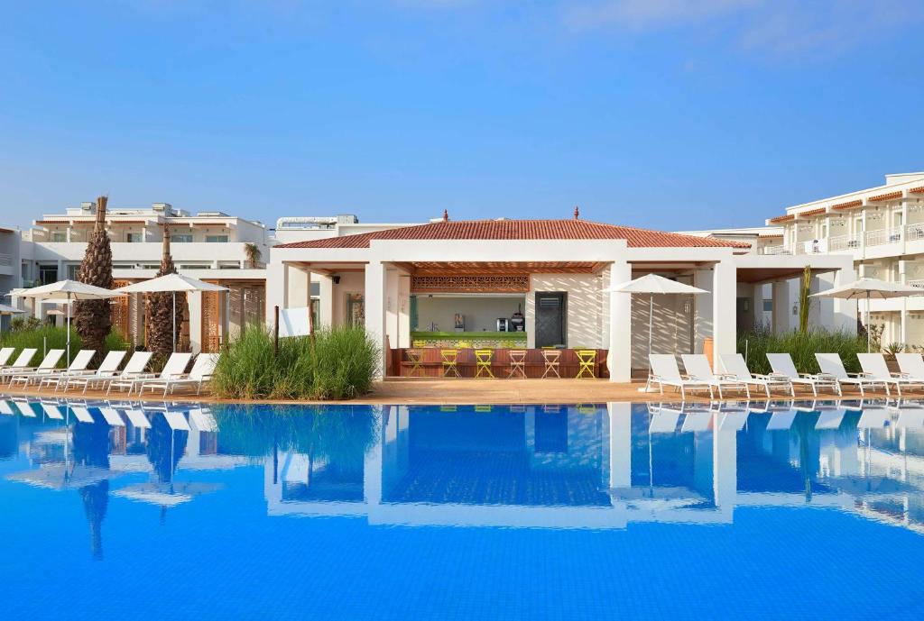 a villa with a swimming pool in front of a building at Radisson Blu Resort Saidia Beach in Saïdia