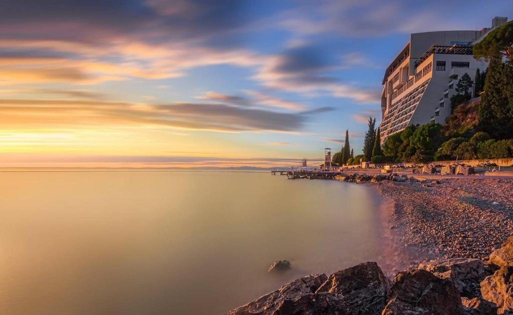 a view of a beach at sunset with buildings at Grand Hotel Bernardin in Portorož