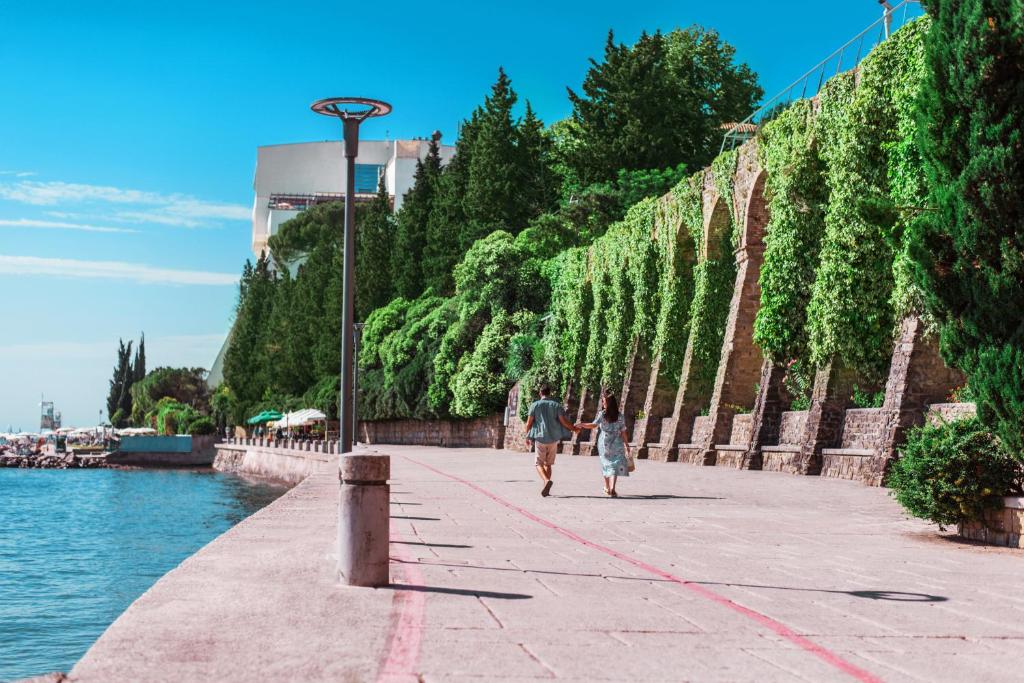 two people walking down a sidewalk next to the water at Grand Hotel Bernardin in Portorož